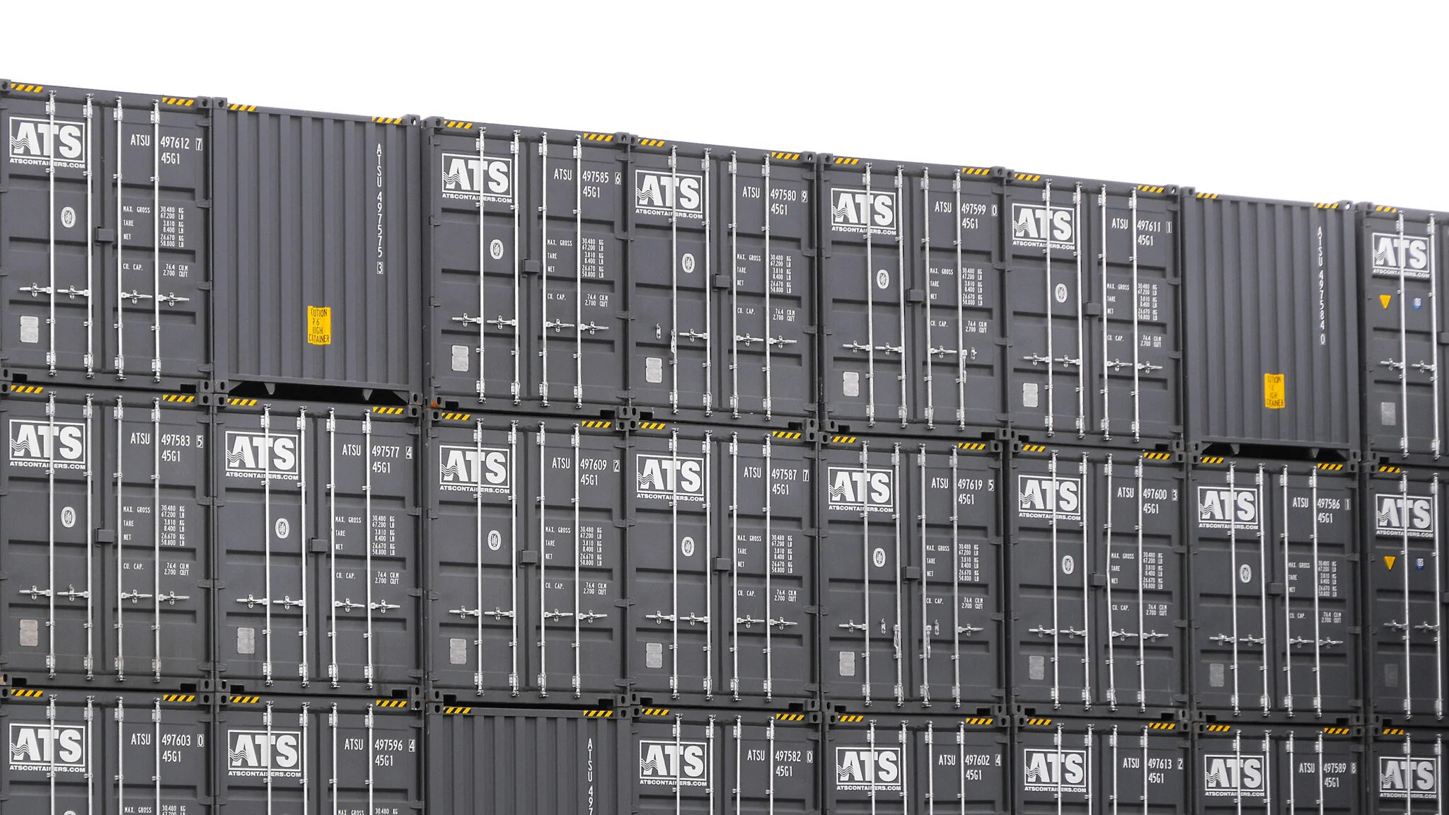 New grey shipping containers (20ft and 40ft units) stacked in a shipping container lot.