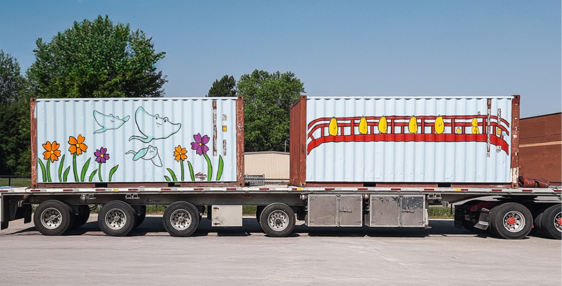 Colorful murals on ATS shipping containers loaded on a truck for delivery for the North of 60 Project's effort to support Northern communities across Canada with durable containers.