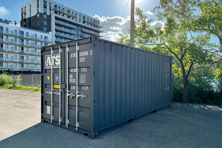 20-ft shipping container for sale, used as secure on-site storage in a parking lot for construction tools and equipment.