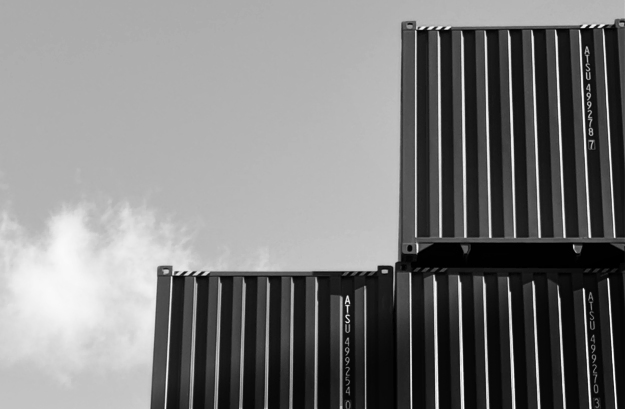 Stacked metal shipping containers in a container yard—durable steel storage units for sale or rent with delivery available.
