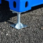 Adjustable steel leveling leg stabilizing a blue shipping container on a gravel job site