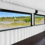Intérieur d’un conteneur kiosque de 20 pi avec murs blancs, plancher noir et mécanisme de volet roulant