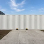 Side view of a light grey 40 ft high cube side door shipping container in a container yard