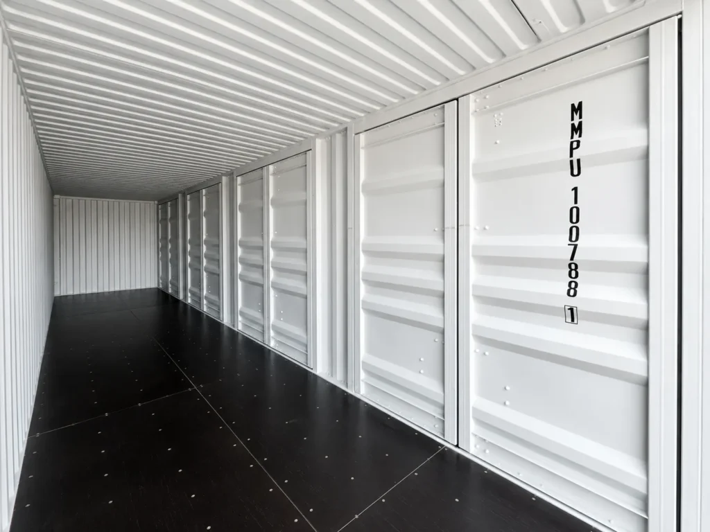 Interior of a 40 ft high cube side door container with white walls, closed side doors and black plywood floor