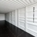 Interior of a 40 ft high cube side door container with white walls, closed side doors and black plywood floor